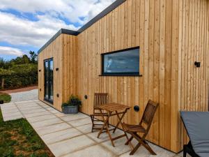 un edificio de madera con una mesa y sillas en un patio en The Cadeleigh, en Tiverton