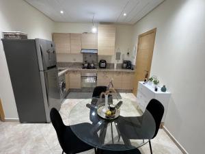 cocina con mesa, sillas y nevera en Résidence RAMOFLORES - Appartement avec piscine - Sidi Rahal, en Sidi Rahal