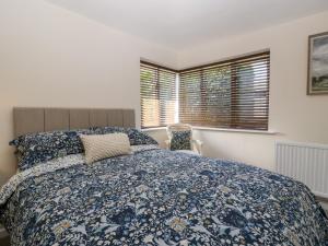 a bedroom with a bed with a blue bedspread and a window at Phocle Ridge in Ross on Wye