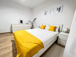 ein weißes Schlafzimmer mit einem großen Bett mit gelber Bettwäsche in der Unterkunft RSA apartment - Comfort near City Centre in Bukarest