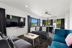 a living room with a blue couch and a tv at Alpine Escape - Elevated Views with Spa in Queenstown