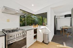 a kitchen with a stove and a large window at Alpine Escape - Elevated Views with Spa in Queenstown