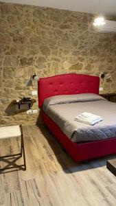 a red bed in a room with a brick wall at Agriturismo Borgo Furma in Enna