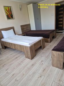 Cama y banco en una habitación con suelo de madera en Centrum Noclegowe II en Bydgoszcz