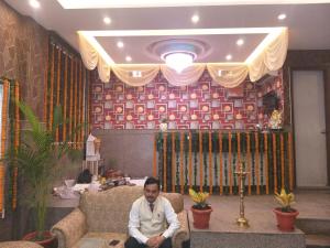 a man sitting on a couch in a living room at Hotel The Best Relax Inn By WB Inn in New Delhi