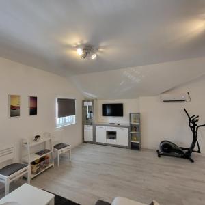 uma ampla sala de estar com paredes brancas e uma televisão de ecrã plano em Apartmani Mia Sorajic em Petrovac na Moru