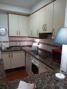 cocina con armarios blancos y mesa con lámpara en Apartamento en casco antiguo Pi y Margal, en Vigo