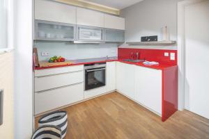 una cocina con armarios blancos y encimeras rojas en Mühlenloft, en Norderney