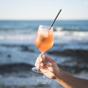 osoba trzymająca drinka przed oceanem w obiekcie Hotel Riviera w mieście Bari