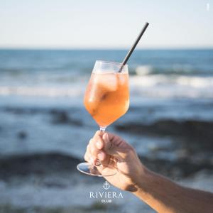 a person holding a drink in front of the ocean at Hotel Riviera in Bari