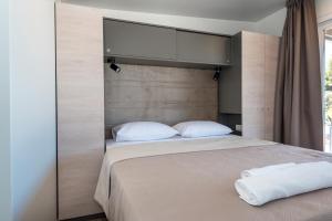 1 dormitorio con 1 cama grande con almohadas blancas en CAMP ADRIATIC MOBILE HOMES - PRIMOŠTEN, en Primošten