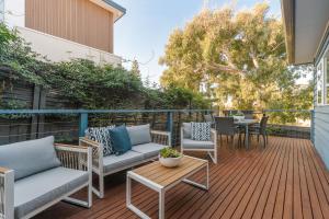 a patio with chairs and a table on a deck at Seaford Luxe Beach House 2023 BDC Traveller award winner in Seaford