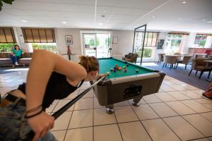 a woman playing pool in a living room at Hostellerie Saint Vincent Beauvais Aeroport in Beauvais