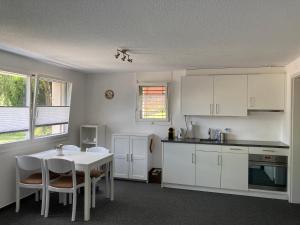 a kitchen with white cabinets and a table with chairs at FeWo-Studio Linde in Amsoldingen