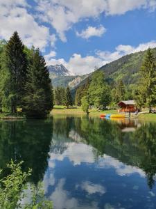 a lake with a gazebo and trees and mountains at Les Pierres Blanches 2 pieces cosy et fonctionnel in Les Contamines-Montjoie