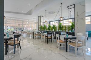 un restaurante con mesas blancas, sillas y plantas en Delfina Tropic Beach en Georgioupolis