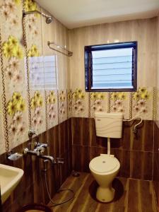 a bathroom with a toilet and a window at Hotel Adinath in Mahabaleshwar