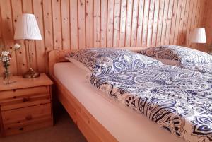 a bed with a blue and white comforter and a night stand at Landhof Kützin Ferienhaus 6 Specht 