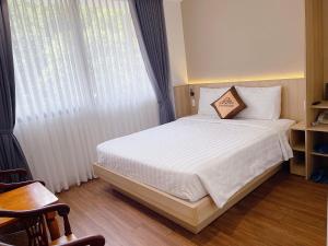 a bedroom with a bed with white sheets and a window at Thanh Bình Hotel - 47 Y Bih - BMT in Buon Ma Thuot