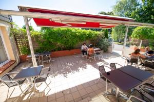 a group of people sitting at tables and chairs on a patio at Hostellerie Saint Vincent Beauvais Aeroport in Beauvais