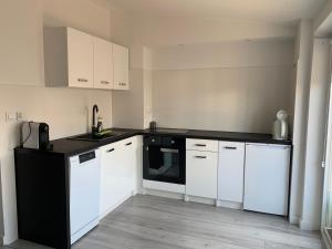 a kitchen with white cabinets and a black counter top at Apartament w Gdyni u podnoża Kamiennej Góry in Gdynia