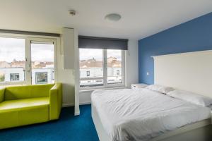 a bedroom with a large bed and a yellow chair at Destiny Student – Murano (Campus Accommodation) in Edinburgh
