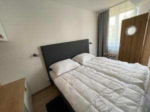 una camera da letto con un grande letto con lenzuola bianche di Apartman 511 a Lipno nad Vltavou