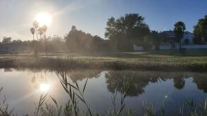 un cuerpo de agua con el sol reflejándose en él en Spindlewood Barn Accommodation, en Hopefield