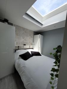 a bedroom with a large white bed with a skylight at B&B Mooi Betuwe in Tiel