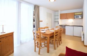a kitchen and dining room with a wooden table and chairs at Les Balcons PROCHE PARC NATIONAL VANOISE appartements 2 pieces 5 pers in Termignon