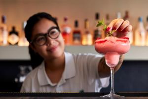 a woman holding a strawberry in a cocktail glass at Dom Jose Beach Hotel (Plus) in Quarteira