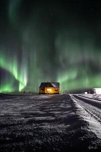 a house in the middle of a field under the aurora at Efri-Gegnishólar in Selfoss