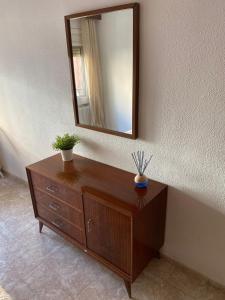eine hölzerne Kommode mit einem Spiegel an der Wand in der Unterkunft Cozy Apartment in Centre of Alicante near Plaza de Toros in Alicante