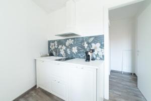 een witte keuken met een wastafel en bloemenbehang bij LA CORTE SUL LAGO in Merone