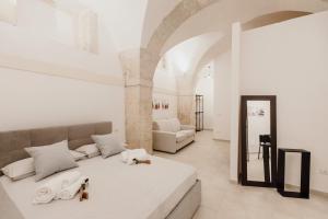 a white bedroom with a bed and a living room at I Dammusi di Via Vittorio Veneto in Syracuse