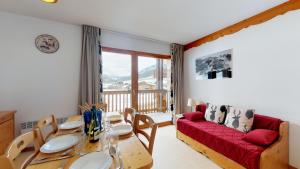 a living room with a table and a red couch at Les Balcons PROCHE PARC NATIONAL VANOISE appartements 2 pieces 6 pers CABINE in Termignon