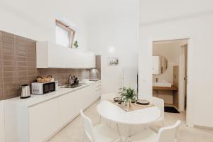 uma cozinha branca com uma mesa e cadeiras brancas em I Dammusi di Via Vittorio Veneto em Siracusa