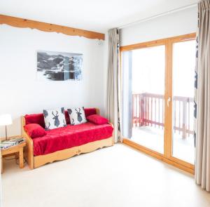 a living room with a red couch and a balcony at Les Balcons PROCHE PARC NATIONAL VANOISE appartements 2 pieces 6 pers CABINE in Termignon