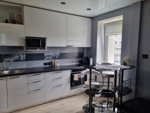a kitchen with white cabinets and a counter with stools at Pas Romaną in Zarasai