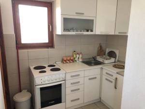a white kitchen with a stove and a window at Vikendica Drina Hill Loznica in Loznica