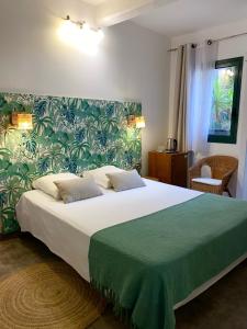 a bedroom with a large bed with a green blanket at Logis Hôtel La Fenière in La Bouilladisse