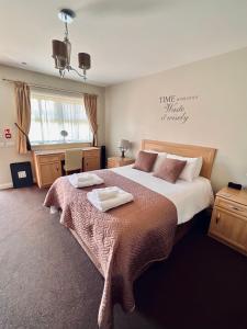 a bedroom with a large bed with two towels on it at The Reindeer Inn in Sandtoft
