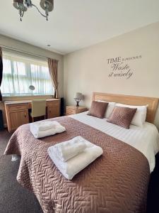 a bedroom with a large bed with two towels on it at The Reindeer Inn in Sandtoft