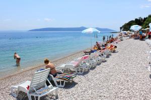 a group of people sitting in lawn chairs on a beach at Apartments by the sea Moscenicka Draga, Opatija - 17381 in Mošćenička Draga