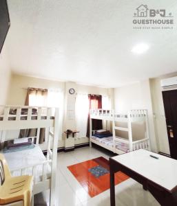 a room with three bunk beds and a table at B&J Guesthouse and Tours in Tagbilaran City