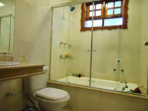 a bathroom with a shower and a toilet and a sink at Pousada do Castelo in Monte Verde +20 photos