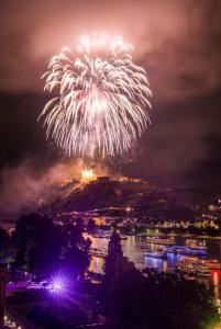 a firework display over a river with a city at Das Loreley Weinstuebchen in Sankt Goarshausen