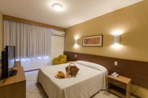 a hotel room with a bed with a hat on it at Atobá Praia Hotel in Balneário Camboriú