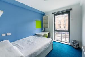 a blue bedroom with a bed and a window at Destiny Student – Shrubhill (Campus Accommodation) in Edinburgh