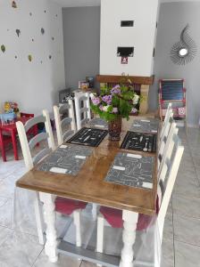 una mesa de madera con sillas y un jarrón de flores. en Location villa saisonniere a la campagne, en Saint-Théodorit